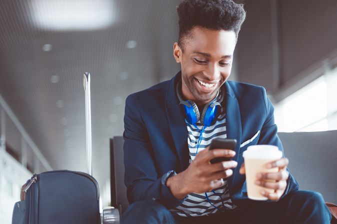 Young man waiting at the airport lounge using mobile phone