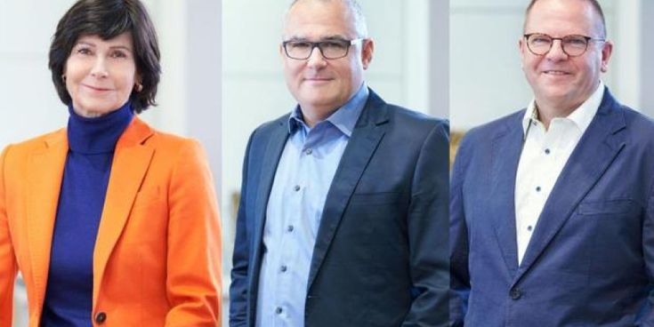 Drei Personen (von links nach rechts Dr. Ute Dallmeier, Dirk Hamacher, Frank Steuer) in Businesskleidung stehen nebeneinander und lächeln – Symbol für das Leitungsteam eines etablierten Unternehmens.
