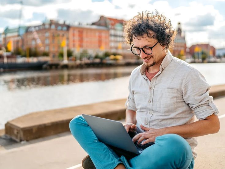 Geschäftsreisender arbeitet am Laptop am Wasser während einer privaten Reiseverlängerung