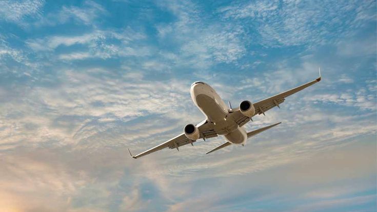 fliegendes Flugzeug von unten, Sonnenuntergang im Hintergrund