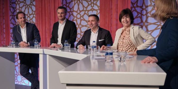 Mehrere Personen diskutieren auf einer Bühne während einer Podiumsdiskussion – Symbol für Austausch und Fachdialog in der Tourismusbranche.