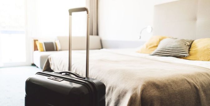 Koffer steht am Bett im Hotelzimmer