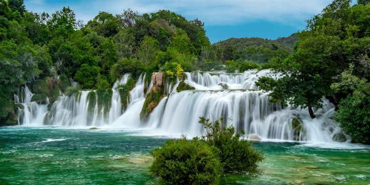 Majestätische Wasserfälle im Krka-Nationalpark in Kroatien, umgeben von üppiger grüner Vegetation und türkisblauem Wasser.