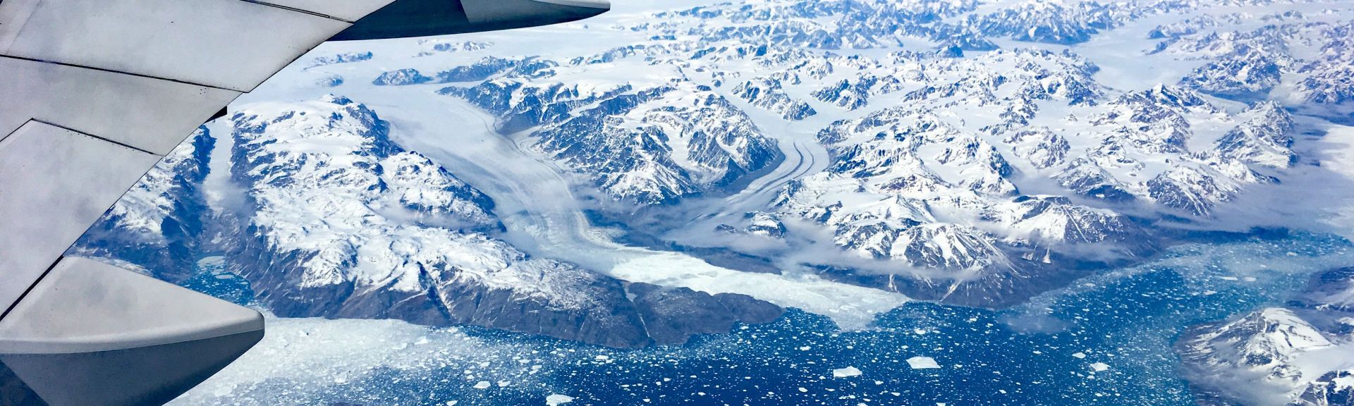 Flugzeug Tragfläche am Himmel über Schnee bedeckten Bergen