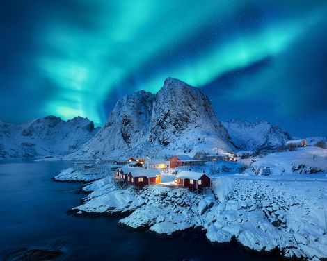Polarlichter über einer verschneiten Landschaft mit typischem roten Holzhäuschen