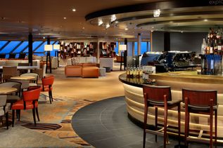 Eine elegante Lounge auf einem Kreuzfahrtschiff mit moderner Bar, gemütlichen Sitzbereichen und großer Fensterfront mit Meerblick.