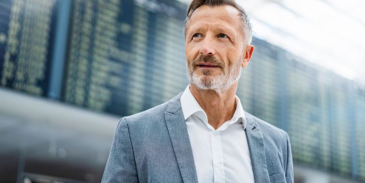 Geschäftsreisender hält Smartphone am Flughafen