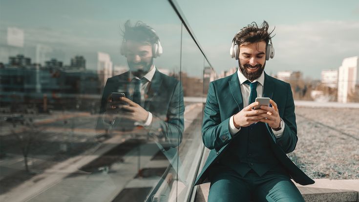 Geschäftsmann mit Handy und Kopfhörern auf Dachterrasse
