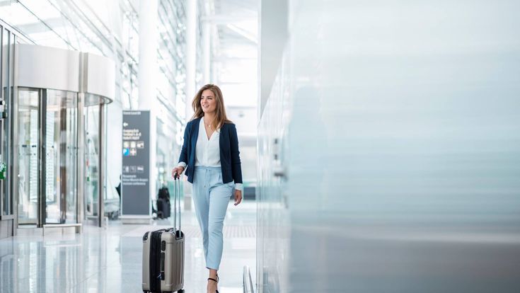 Geschäftsfrau mit Handgepäckskoffer am Flughafen