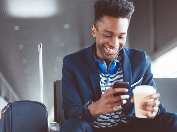 Young man waiting at the airport lounge using mobile phone
