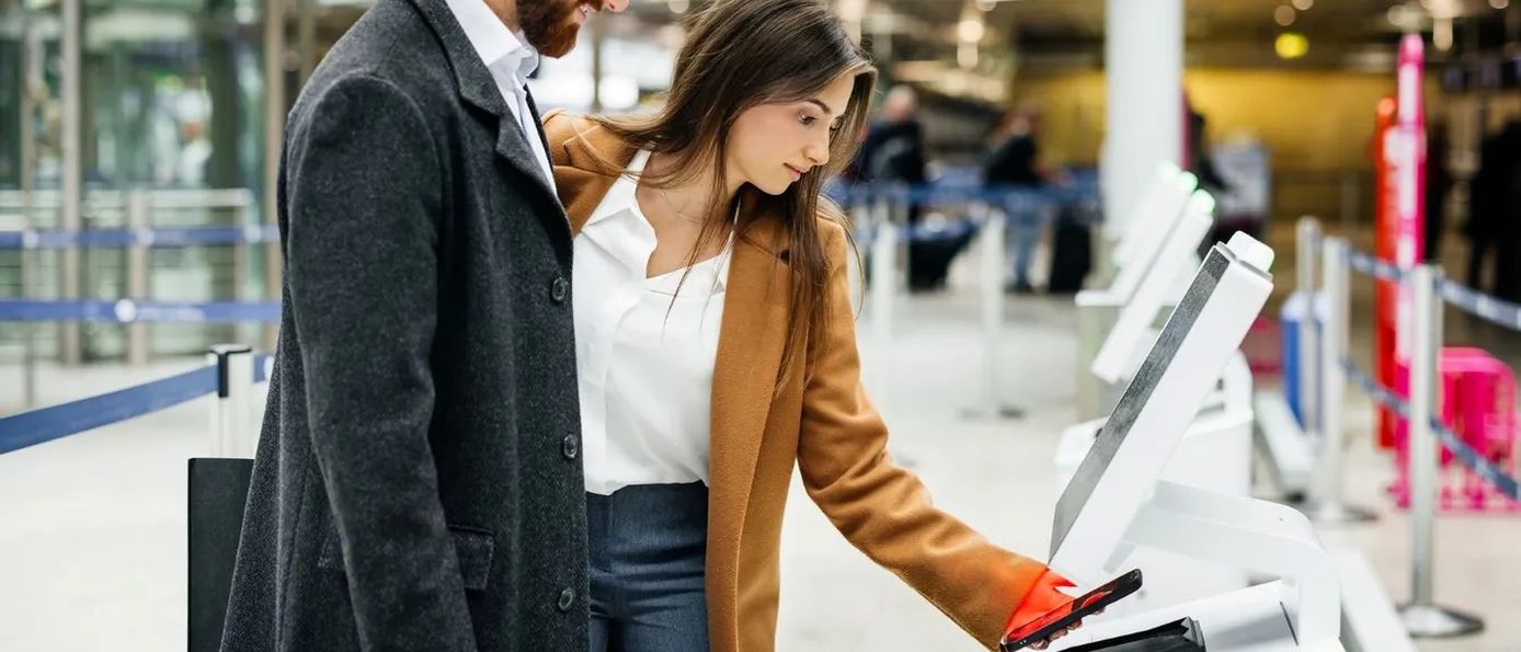 Paar nutzt digitales Check-in-Terminal am Flughafen