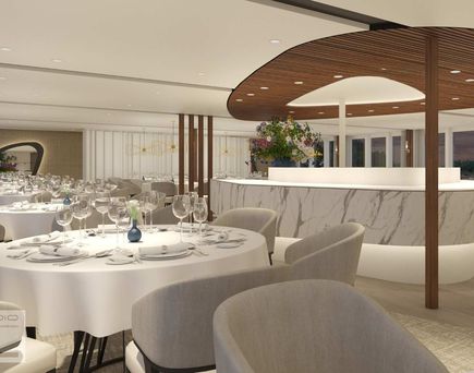 Eine helle und einladende Schiffskabine mit einem komfortablen Bett, eingebauten Schränken, einer kleinen Sitzecke und einem großen Flachbildfernseher.