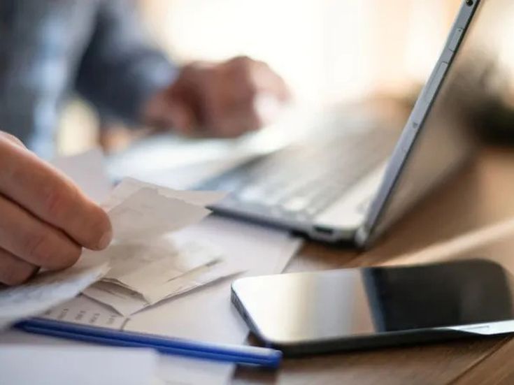 Geschäftsreisender sortiert Belege und Quittungen neben Laptop und Smartphone