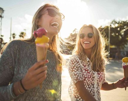 Lachende Frauen mit Eiscreme im Sommer