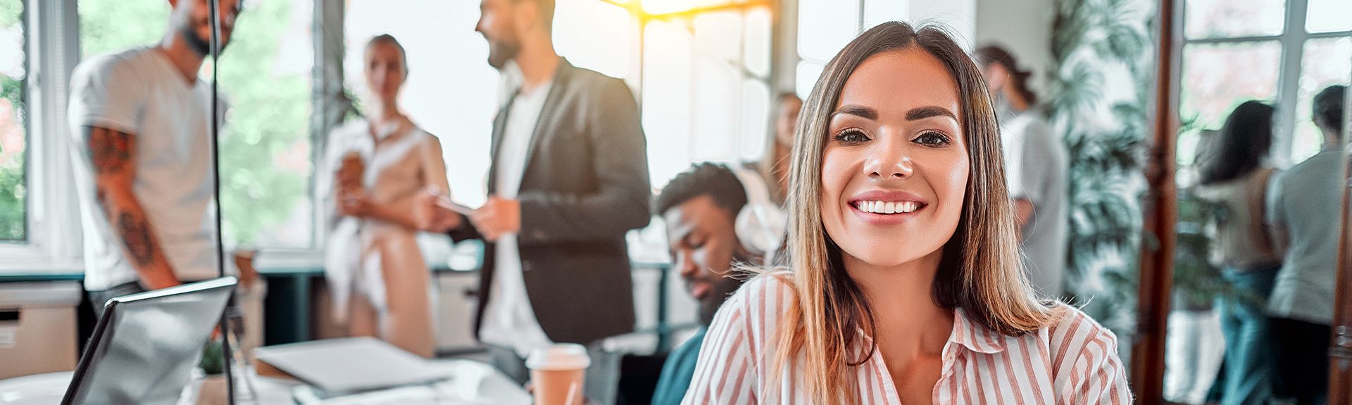 Lachende Frau im alternativen Büro mit Kaffeebecher und Kollegen