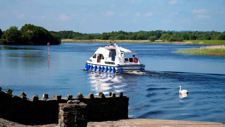 Kleines Motorboot fährt über einen ruhigen See mit grüner Landschaft im Hintergrund.