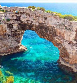 Natürlicher Felsbogen über türkisblauem Meer an einer sonnigen Küste.