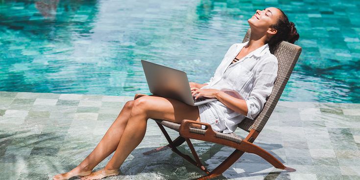 Entspannte Geschäftsfrau mit Laptop auf Klappstuhl am Pool