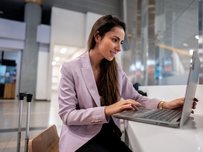 Geschäftsreisende arbeitet mit Laptop im Flughafen