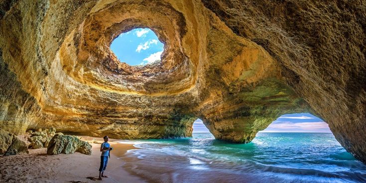 Eindrucksvolle Meereshöhle an der Algarve mit natürlichen Felsbögen, türkisblauem Wasser und Öffnung in der Höhlendecke.