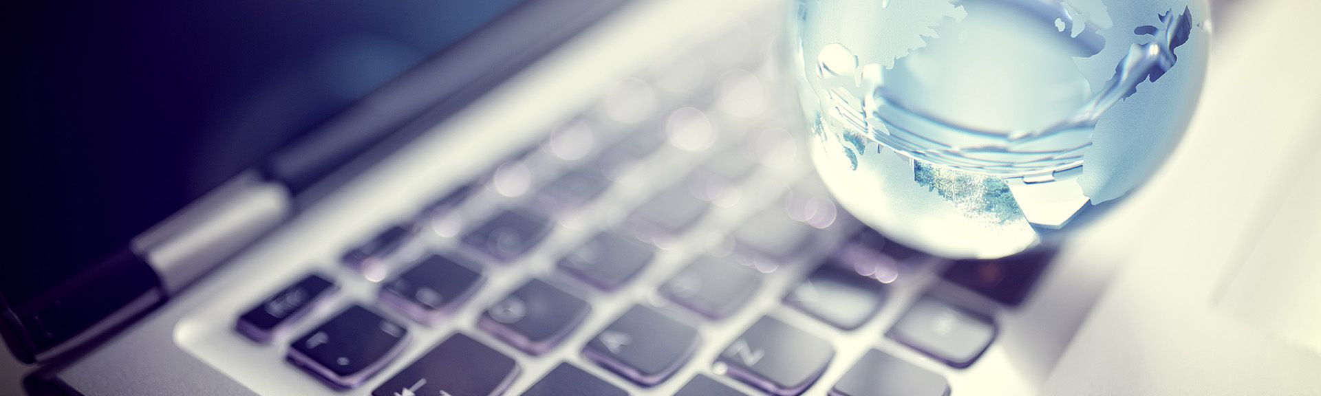 Hellblaue Weltkugel aus Glas liegt auf Tastatur
