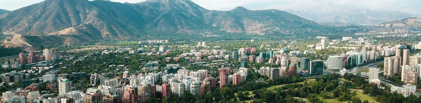 Grüne Natur und Stadt vor einem Berg in Chile
