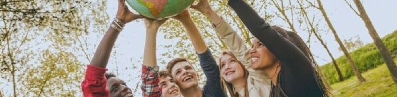 Fünf junge Menschen halten gemeinsam einen Globus in die Höhe und symbolisieren Teamgeist und Weltoffenheit.