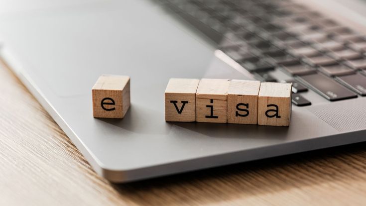 Holzwürfel mit dem Schriftzug „e visa“ auf einem Laptop.