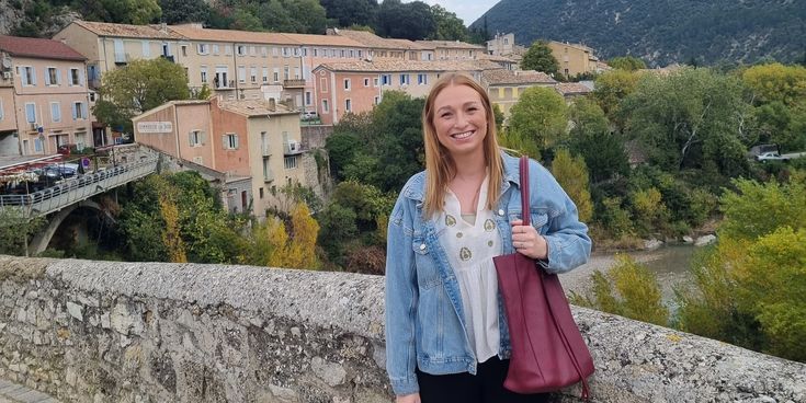 Raya Hemme auf einer Brücke mit kleinen Häuschen im Hintergrund