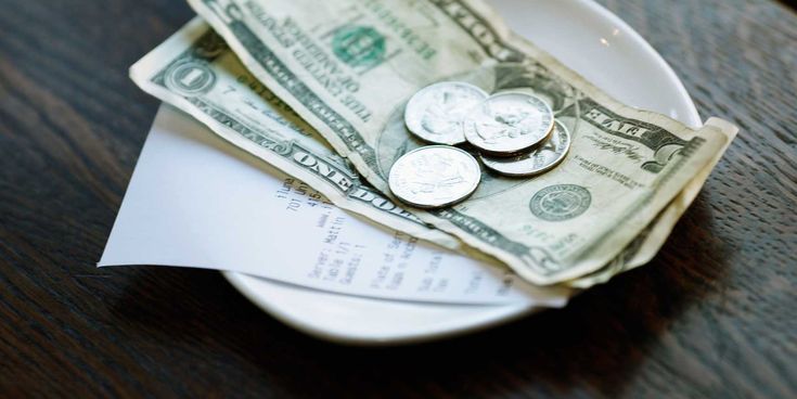 Dollarnoten und Münzen auf einem Teller mit einer Rechnung