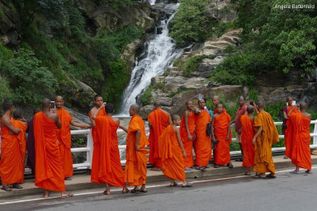 Rotes Gewand tragende Einheimische stehen vor Wasserfall auf Sri Lanka