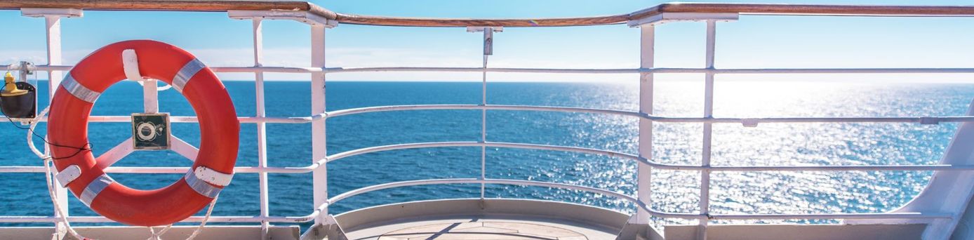Blick vom Deck eines Kreuzfahrtschiffs auf das Meer mit blauem Himmel und rotem Rettungsring – Symbol für Reisen, Freiheit und Sicherheit auf See.