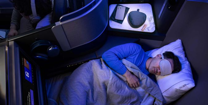 Mann mit Augenmaske schläft in der Polaris Business Class von United im Flatbed