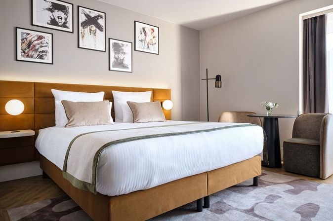 Modernes Hotelzimmer bei Leonardo Hotels mit Doppelbett, Sitzbereich und Wandbildern.