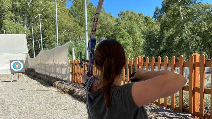 Frau schießt mit dem Bogen auf eine Zielscheibe